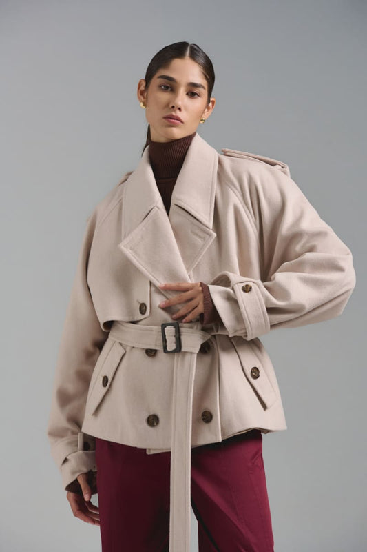 Chaquetón tipo trench corto. Oversize, confeccionado en paño sastre. Presillas en puño desmontables y ajustables. Charreteras en hombro y lazo del mismo paño desmontable. Botones al frente jaspeados y hebillas a tono. Composición: 50% Lana - 50% Poliéster. Interiormente forrado en tafeta jacquard.