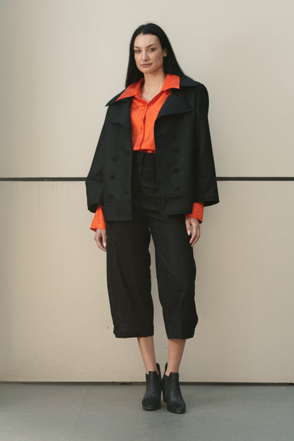 Diseño geométrico de calce amplio y talla unica, con fuerte influencia asiática. Cuello redondo, botonadura simple, aberturas en puños y bolsillos, tablón trasero. Paño 100% lana de Bellavista Tomé, forrada en rayón/viscosa de Strobel Linnings.