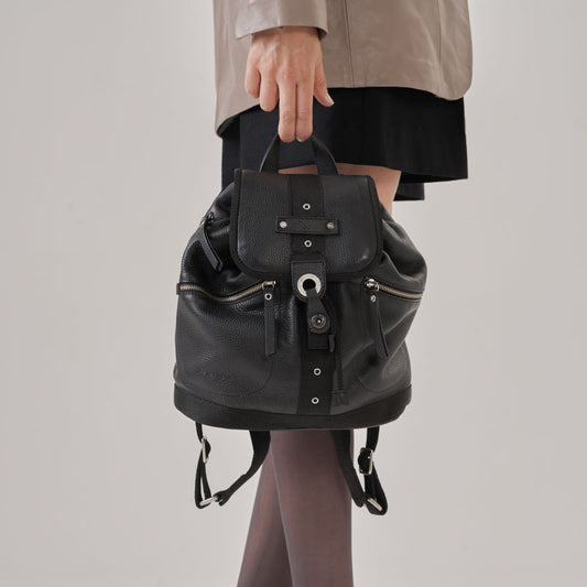 Mochila con correas de tela, 2 bolsillos frontales y uno trasero acolchonado, todos con cierre. Solapa con broche y cierre con amarre.