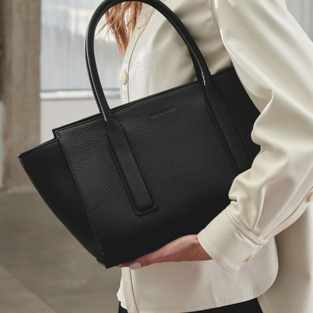 Cartera de hombro de gran capacidad, de estructura rígida y resistente. Manijas repujadas, amplio interior con bolsillo con cierre y tira portallaves.