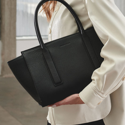Cartera de hombro de gran capacidad, de estructura rígida y resistente. Manijas repujadas, amplio interior con bolsillo con cierre y tira portallaves.