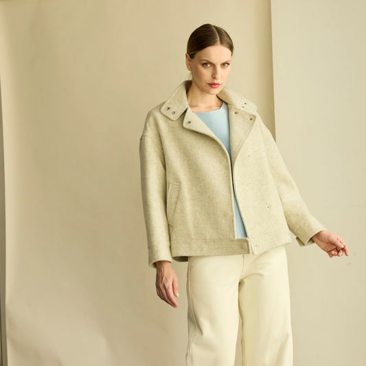 Chaqueta corta de paño gris claro. De silueta tipo bomber, confeccionado en paño sastre premium. Broches de presión en el frente y puños. Bolsillos laterales.
